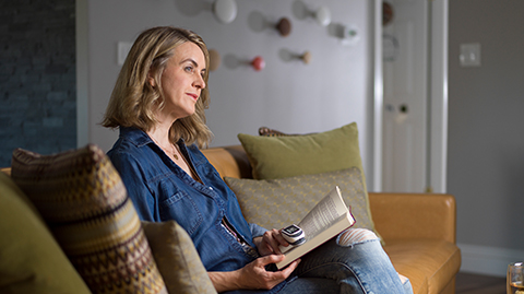 Individual in home environment reading on couch while taking measurements with a MightySat pulse oximeter. 